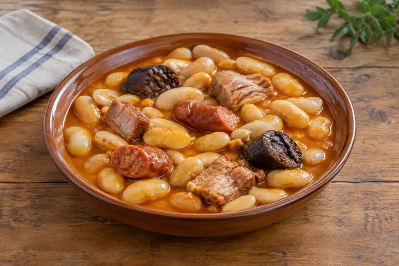 A pot of Asturian bean stew with chorizo, morcilla and pork in an orange broth